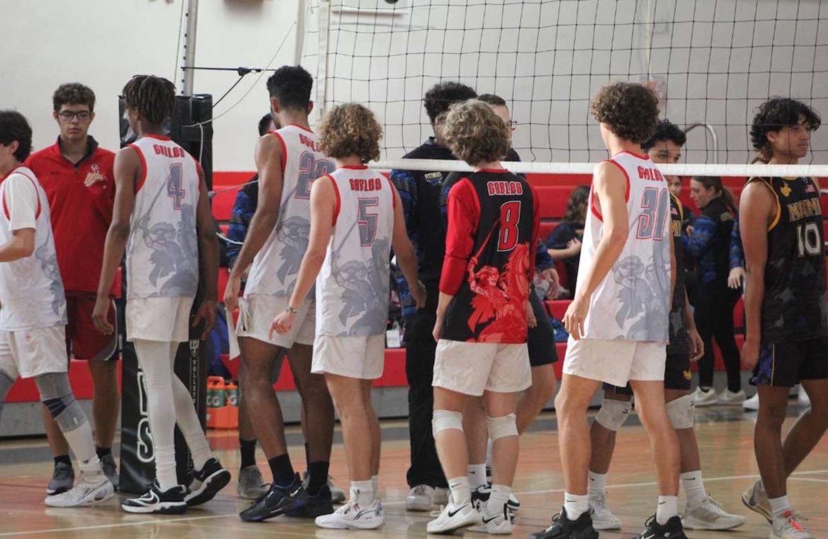 Commemorating the end of their game, the Varsity Boys Volleyball team and the Boys Varsity Miami High Volleyball team line up for their handshake lines. 